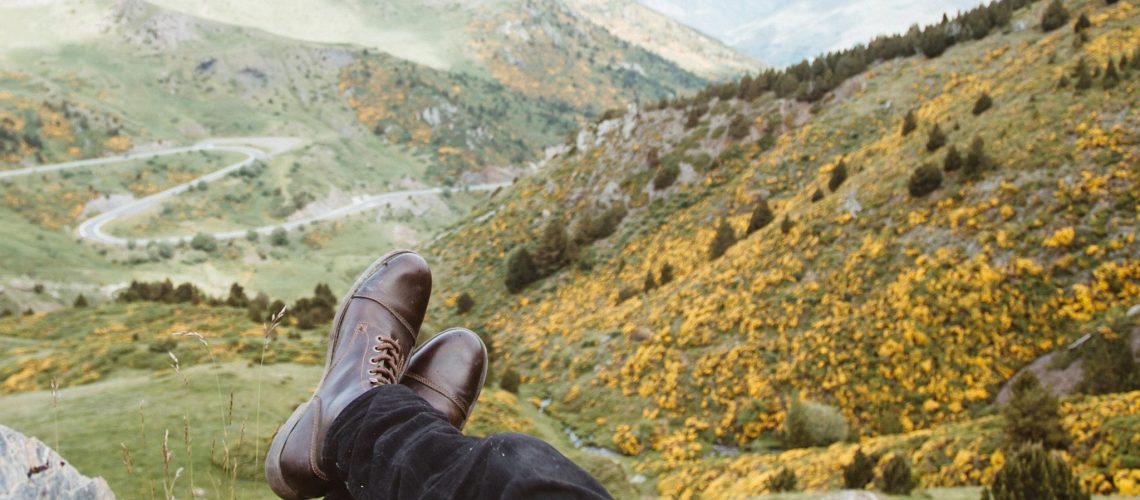a man sits on a mountain, his legs and feet are shown